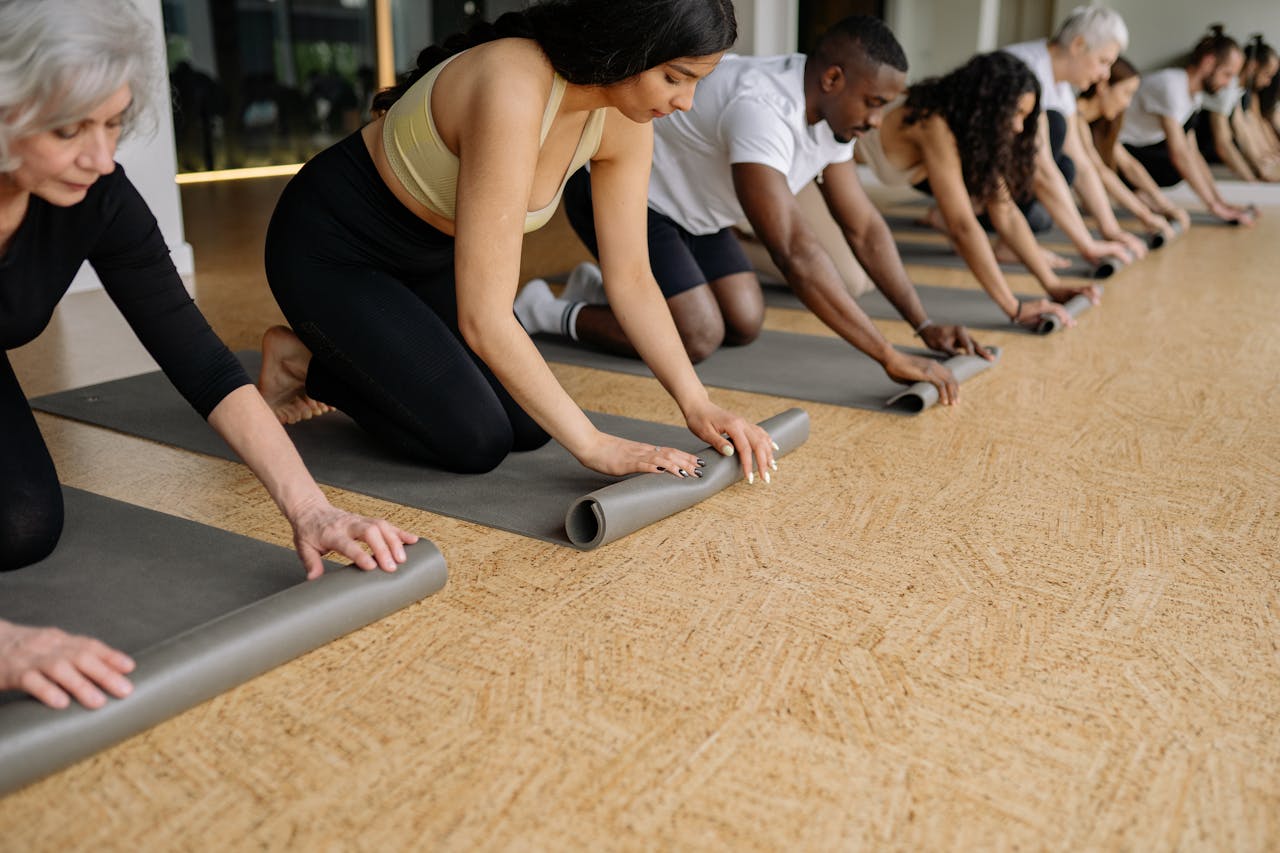 heros-img A diverse group of adults rolling yoga mats in a studio before practice, promoting fitness and wellbeing.